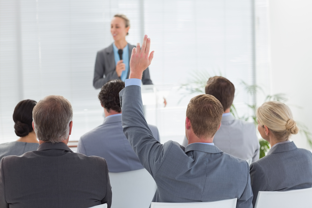 Pretty businesswoman talking in microphone during conference in meeting room
